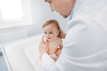 Delicate excellent pediatrician carefully checking his patient