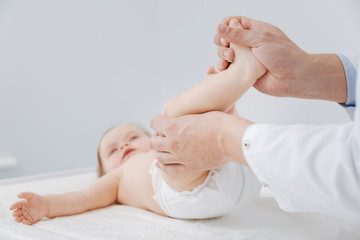 Fototapeta na wymiar Neat professional pediatrician checking toddlers joints