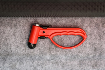 Red evacuation emergency break glass hammer tool on public transport.