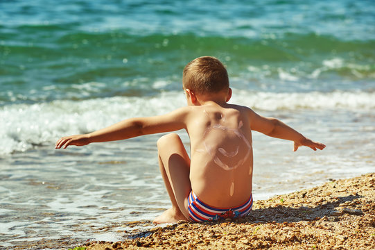 Rear view of boy at sea enjoying the sun on the beach. Sunscreen