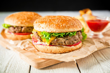 Hamburger with beef, sauce and french fries on wood table. Flat lay. Top view. American tasty food