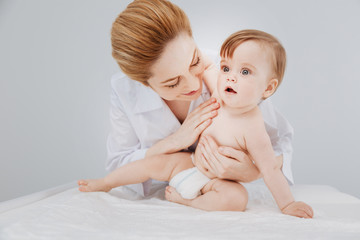 Positive qualified pediatrician enjoying her work with adorable patient