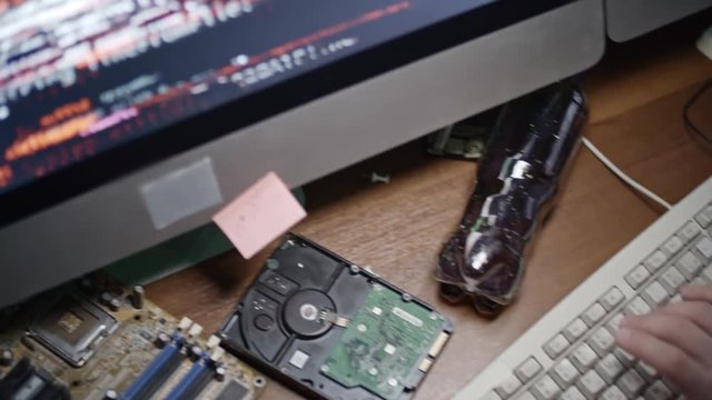 Tracking shot hands of male hacker typing on keyboard while working on programming code on computer