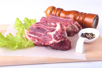 Raw beef edges, lettuce leaf, pepper grinder and spices on wooden desk isolated on white background from above and copy space. ready for cooking.