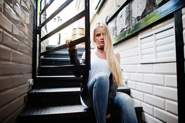 Stylish blonde woman wear at jeans, choker and leather jacket at street near stairs. Fashion urban model portrait.