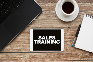 Tablet on desktop with sales training text.