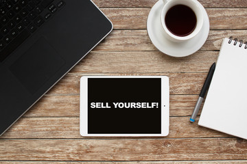 Tablet on desktop with sell yourself! text.