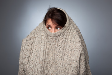 A girl with a social phobia hides her face in a sweater. She looks frightened around