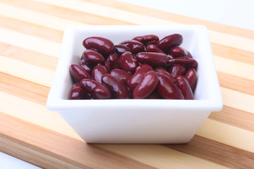 Heap of canned red kidney beans in the sauce in white bowl. vegetarian food. Phaseolus vulgaris.