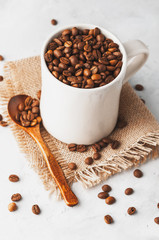 Conceptual Breakfast, Cup with coffee beans on a white concrete background.