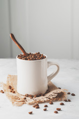 Conceptual Breakfast, Cup with coffee beans on a white concrete background.