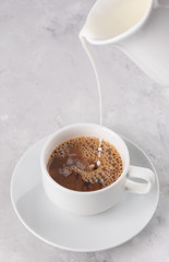 The process of pouring in a Cup of coffee milk from the milkman, morning Breakfast, white background