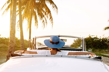 Beautiful woman in blue hat and white retro cabriolet