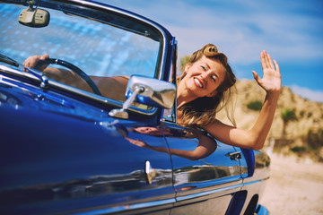 Beautiful happy woman sitting in retro cabriolet car