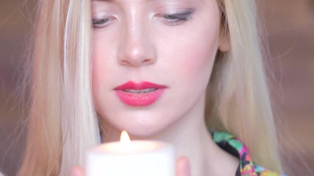 Sad attractive young women blows out a candle. Feel pain, lost someone. Make a wish