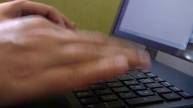 Caucasian man hands printing on laptop keyboard. Closeup view of computer with green wall behind. Office scene. 