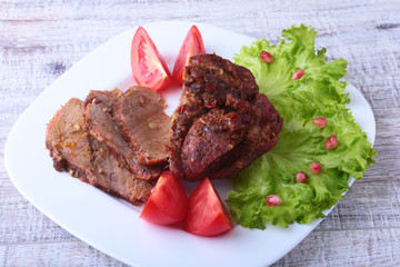 Steak of grilled meat with tomato, lettuce and beans pomegranate on white plate.