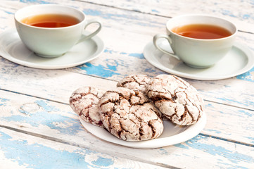 Two cups of tea and saucer with cookies on the old wooden table.