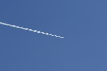 Airplane condensation trail going on blue sky