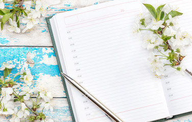 Notepad, pen and branches with cherry blossom on the table.