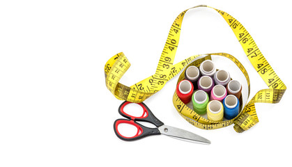 Colored sewing threads with measuring tape and scissors on the white.
