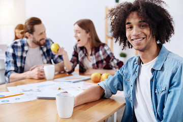 Delighted positive guy having some refreshing coffee during a break