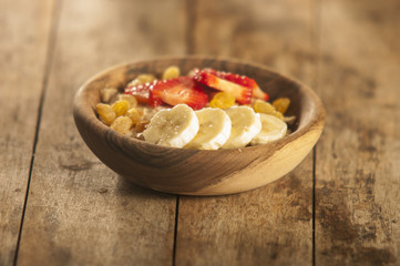 oatmeal porridge with strawberry and banana in wood bowl