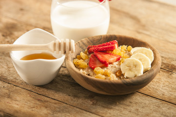 oatmeal porridge with strawberry and banana in wood bowl