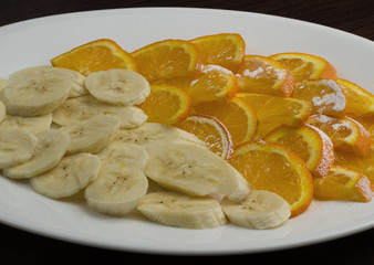 Orange and banana slices on a plate isolated