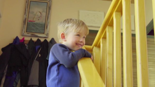 Funny little boy plays and poses for the camera as he walks down the stairs past the camera