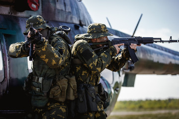 Photos of a group of military men with a gun in front of a helicopter