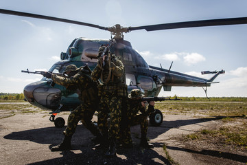 Fototapeta na wymiar Photos of a group of military men with a gun in front of a helicopter