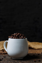 Coffee beans in the cup on wooden background