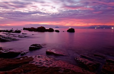 Obraz premium Dramatic dawning sky reflecting on peaceful sea water at the rocky beach of Yilan Coast Geologic Park in northeast Taiwan ~ Beautiful sunrise scenery of a rocky coast in rosy twilight (Long Exposure)
