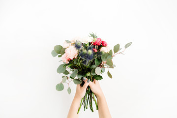 Girl's hands holding beautiful flowers bouquet: bombastic roses, blue eringium, eucalyptus, isolated on white background. Flat lay, top view. Floral composition