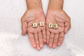 The elderly man is holding the dice with the inscription life. The concept of retirement.