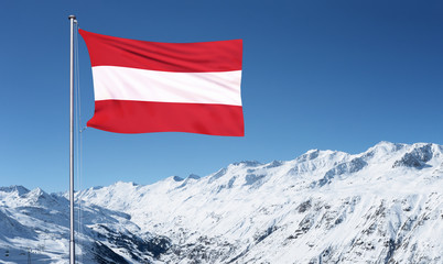 The Austrian flag flying from a metal pole in front of the Oztal Alps in Obergurgl, Austria