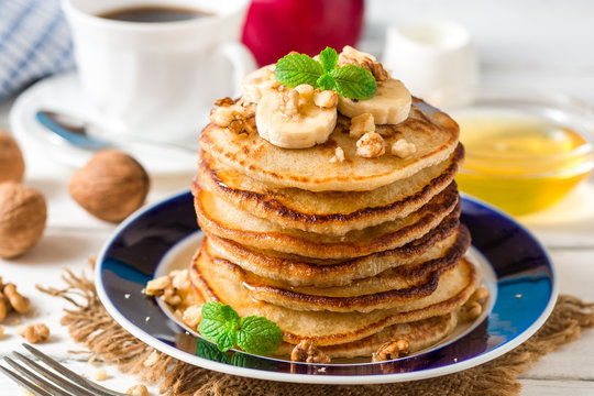 Pancakes with banana, honey, walnuts and mint on plate.
