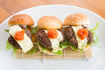 close up of mini burgers with cheese, onion and pickle...
