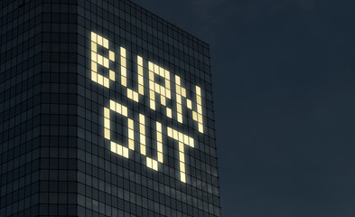 Burnout concept. Exhaustion and stress from too much things to do at job. Stressful overtime job causes mental problems and crisis. Text made by office building window lights at night.