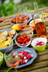 holiday summer brunch party table outdoor in a house backyard with appetizer, glass of rosé wine, fresh drink and organic vegetables