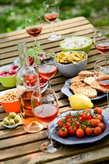 Fototapeta na wymiar holiday summer brunch party table outdoor in a house backyard with appetizer, glass of rosé wine, fresh drink and organic vegetables