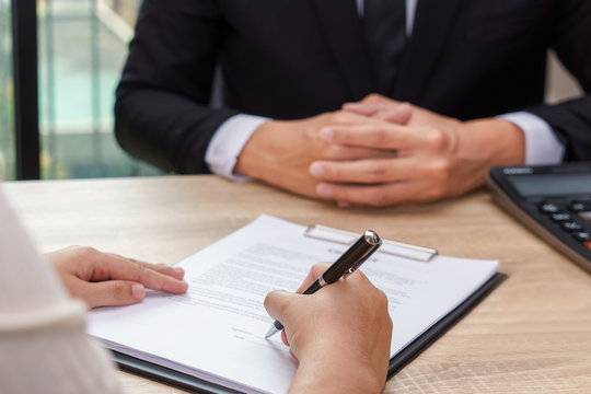 Woman signing contract or loan agreement document with businessman waiting for.