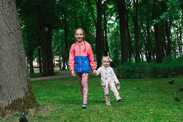 Naklejka na ściany i meble Children walk in the park on a day off. The sun is shining