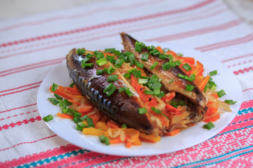 The stuffed mackerel with vegetables and greens on a plate