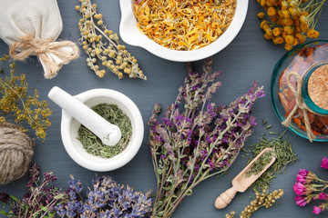 Medicinal herbs, mortar of healing herbs, sachet and bottle of drugs on wooden table. Herbal...