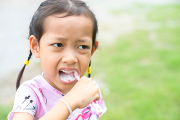 Asia child girl brush their teeth with unhappy.