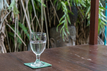 Glass of water on a wooden table in a restaurant. Bali island.