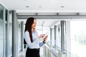 Fototapeta premium Business woman standing and typing on her tablet