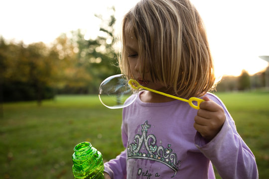 Young girl blowing bubbles outside
